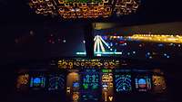 Blick aus einem Cockpit auf die beleuchtete Landebahn