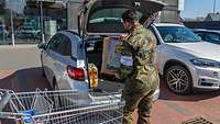 Ein Soldat lädt Einkäufe in einen Kofferraum