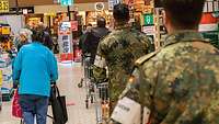 Zwei Soldaten stehen mit je einem Einkaufswagen in einer Supermarktschlange