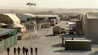 Container, Zelte, Militärfahrzeuge und Soldaten in einem Feldlager