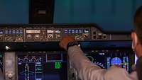 Pilot bedient einen Knopf im Cockpit