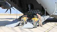 Vier Soldaten stehen an der Laderampe und verladen verzurrtes Material in das Transportflugzeug A400M
