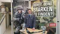 Der Soldat Danny Köppen in grauer Heeresuniform. Hinter ihm ein Banner, auf dem steht "Bereit, deine Stärken zu finden?"