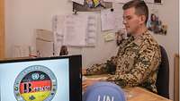 Ein deutscher Soldat sitzt in einem Büro an einem Computer