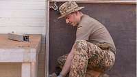 Ein deutscher Soldat hockt am Boden und baut ein Bühnenelement ab