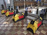 Vier Fotos und vier Särge, mit Helm und in die Bundesdienstflagge eingehüllt, stehen nebeneinander in einer Kirche