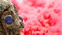 Ein deutscher Soldat steht vor einer großen roten Nebelwand