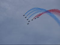 Acht Maschinen der Patrouille de France in der Luft mit Kondensstreifen in Blau, Weiß und Rot.
