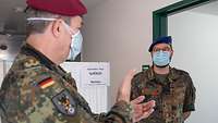 Zwei Soldaten mit Schutzmasken sprechen miteinander.