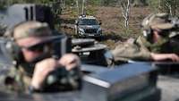 Im Vordergrund zwei Soldaten in Fahrzeugluken mit Fernglas, hinten ein Schiedsrichterfahrzeug.