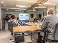 General Eberhard Zorn sitzt mit Soldaten in einem Konferenzraum bei einem Powerpoint-Vortrag.