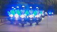 Mehrere Mototräder fahren mit Blaulicht in Formation auf einer Straße
