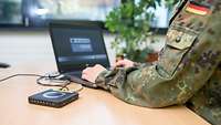 Ein Soldat sitz an einem mobilen Arbeitsplatz
