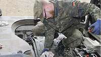 Ein Soldat prüft den Ölstand eines Schützenpanzers