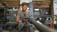 Ein Soldat überprüft Bauteile einer Waffe in einer Werkstatt