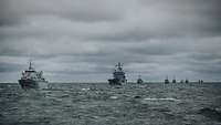 Mehrere graue Kriegsschiffe fahren hintereinander auf See.