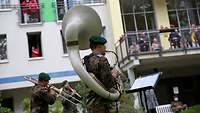 Soldaten spielen auf Blasinstrumenten vor einem Seniorenheim.