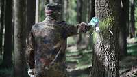 Ein Soldat sprüht eine Markierung an einen Baum