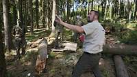 Ein Mitarbeiter des Forstamtes weist im Wald die Soldaten in die Arbeit ein. 