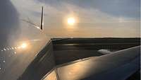 Ein Flugzeug auf dem Rollfeld, das Licht der aufgehenden Sonne reflektiert am Rumpf und auf dem Flügel