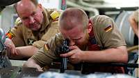Ein Soldat schaut mit einem Endoskop in einen Zylinder des Schiffsmotor
