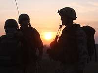 Silhouetten von drei Soldaten bei Sonnenaufgang