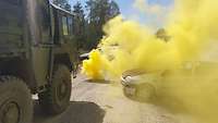 Ein Bundeswehr-Lkw ist vor einer dichten, gelben Rauchwolke zum Stehen gekommen.