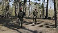 Zwei Soldaten der Feldjäger laufen in einem Waldstück hintereinander Streife