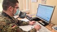 Ein Soldat sitzt an einem Computer. 