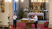 Eine uniformierte Frau und ein uniformierter Mann spielen Flöte in einer Kapelle.