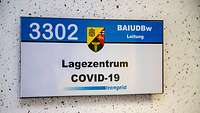 Ein Schild an einer Gebäudewand mit der Afschrift „Lagezentrum Covid-19“.