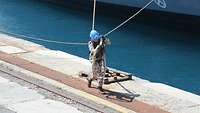 Ein Soldat zieht eine Festmacherleine auf die Pier