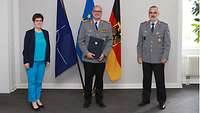 Verteidigungsministerin Kramp-Karrenbauer, Dr. Holtherm und Dr. Baumgärtner stehen vor den Flaggen der NATO, EU und Deutschlands