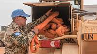 Ein Soldat prüft Material auf seinem Fahrzeug, in der Hand hält er einen orangefarbigen Schlauch