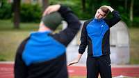 Ein Soldat im Trainingsanzug dehnt seinen Nacken, die um ihn Herumstehenden machen die Übung nach.