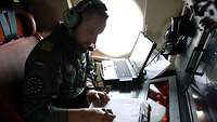Ein Soldat sitzt im Flugzeug und schreibt auf ein Blatt Papier