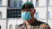 Stabsfeldwebel Karsten Kress steht mit Mund-Nase-Schutz vor einem Gebäudeteil des Bundeswehrkrankenhauses Berlin.