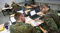 Mehrere Soldaten im Gespräch, vor Computern sitzend