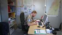 Ein Militärseelsorger sitzt an einem Schreibtisch und bereitet seine Predigt vor