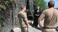 Ein Militärpfarrer begrüßt zwei Soldaten vor dem Kirchenzelt