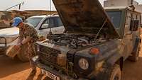 Ein Soldat reinigt den Luftfilter eines militärischen Fahrzeugs