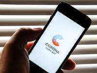 Eine Hand hält ein Smartphone, auf dem das Logo der Corona-Warn-App der Bundesregierung angezeigt wird
