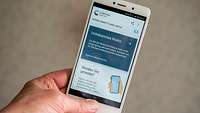 Eine Hand hält ein Smartphone, auf dem die Corona-Warn-App der Bundesregierung angezeigt wird
