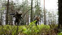Zwei Soldaten laufen mit ihrer Ausrüstung durch den Wald