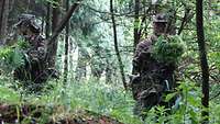 Ein Soldat tarnt seinen Helm mit Gestüb im Wald