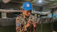 Ein deutscher Soldat mit einer blauen UN-Mütze beschriftet ein Probenröhrchen, im Hintergrund Wasserbecken