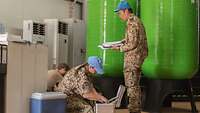 Zwei deutsche Soldaten mit blauen UN-Mützen verpacken Wasserproben