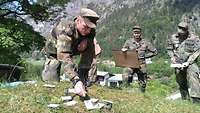 Ein Soldat erklärt mit Karten den Aufbau eines Versorgungspunktes, zwei Soldaten schauen zu.