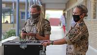 Zwei Soldatinnen stehen vor einem Mischpult und testen die Musikanlage 