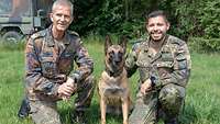 Zwei nebeneinander knienede Soldaten auf einer Wiese – dazwischen sitzt ein Hund 